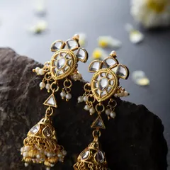 Close-up of traditional Kundan and pearl jhumkas, styled on a dark stone to make the craftsmanship and details pop. This is ideal for a product catalogue.