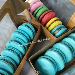 My eggless macarons are a rainbow of flavors, perfect for gifting. Here you can see them packed in custom boxes, with vibrant colors like sky blue, sunshine yellow, and pretty pink, each with a delicious filling.
