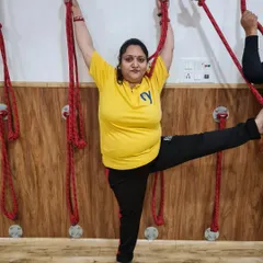 A student uses the yoga ropes to support her in a standing leg extension. This helps improve balance and hamstring flexibility while keeping the standing leg strong and grounded.