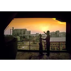 Two figures silhouetted against a sunset view of a factory. This image tells a story of vision and progress, making it ideal for a corporate annual report.