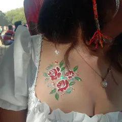 A lovely bouquet of red roses with green leaves and a sprinkle of glitter, painted on the upper back. This is a great placement for off-the-shoulder tops.