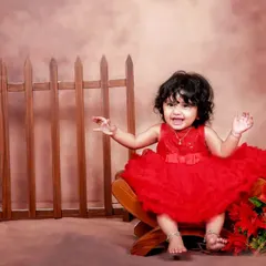 A burst of energy and joy! This little girl in a bright red dress is having a wonderful time in the studio, and her happy expression says it all.