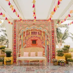 The main seating area for a Haldi ceremony, featuring a stunning custom-printed backdrop inspired by Rajasthani architecture and vibrant tassel hangings.