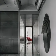 A transitional space in the Vaulted Haus. The polished grey marble floor reflects the vaulted ceiling and sculptural wall art, demonstrating how material choice can enhance the perception of light and space in a narrow passage.