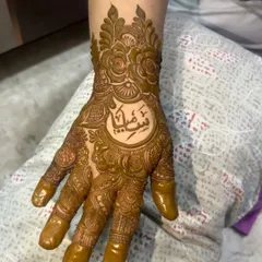 I can beautifully write names and initials in your mehendi. Here, a name in elegant Arabic script is the centerpiece of a detailed floral design on the hand.