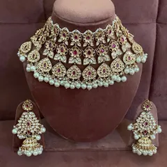 A full view of a modern choker set with ruby-colored stones and pearl drops. This rental set includes matching jhumka earrings.