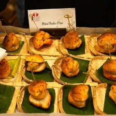 I've transformed Mumbai's iconic street food into an elegant appetizer with these Mini Vada Pavs. They are served on small bamboo plates, offering a nostalgic yet sophisticated bite.