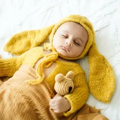 Our little sleepy bunny. Adorable, soft-knit outfits like this yellow bunny costume add a touch of whimsy to newborn photos while keeping your baby comfortable and warm.