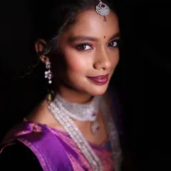 A close-up portrait with a dark background, emphasizing the bride's features and the sparkle of her diamond and silver jewelry. This is a modern, moody style of bridal photography.