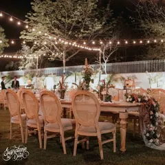 The main dining table was styled for a 'Vintage Romance' theme, with elegant wooden chairs, a long rustic table, and string lights overhead to create a magical, starlit dinner experience.