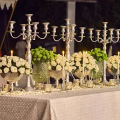 The dining tables were adorned with silver candelabras and arrangements of white roses and green chrysanthemums. This created a regal tablescape that was both elegant and inviting for the Sufi-themed dinner.