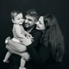 A classic family portrait that feels both timeless and modern. The black and white tones emphasize the emotional connection and the loving gaze shared between parents and their child.