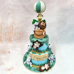 We invite you to a storybook adventure with this two-tiered animal hot air balloon cake. Meticulously crafted jungle animals, including a lion, elephant, and giraffe, are gathered in a woven basket, ready for a whimsical journey, making this a magical centerpiece for a child's birthday celebration.