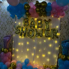 A view of the baby shower backdrop with the lights dimmed to emphasize the warm glow of the fairy lights. This creates a soft and inviting atmosphere for the event.