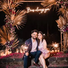 "It was always you." The couple shares a moment with their custom neon sign, the centerpiece of this romantic, candlelit proposal setup.