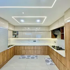 A modern U-shaped modular kitchen designed for ultimate functionality. Notice the seamless blend of wood-tone and high-gloss cabinets, complemented by integrated profile lighting for a bright and efficient cooking space.