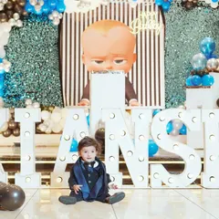A solo shot of the birthday boy amidst his party's awesome decor. This photo highlights both the child and the fantastic "Boss Baby" themed setup with his name in lights.