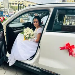 The bride is ready to head to the church. Holding her bouquet of white roses, her makeup looks fresh and perfect for the ceremony ahead.