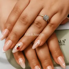 A touch of whimsy on these nude almond extensions. I hand-painted delicate white flowers and added a cute ladybug design on the ring finger for a unique and charming look.