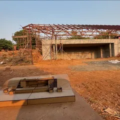 A view of the steel roof structure being erected for the yoga retreat's stage pavilion. In the foreground is a physical model used to explain the complex design to the site team.