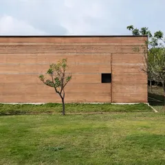 The monolithic rammed earth wall of the H.N. Science Center in Gauribidanur showcases the beauty of building with local soil. The horizontal layers tell the story of its construction, creating a facade that is both monumental and deeply connected to its site.