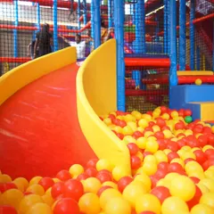 A bright red slide ready for action, ending in a sea of colorful balls. Our slides are a highlight for many kids, offering a thrilling ride every time.