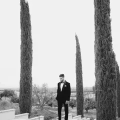 A striking black and white portrait of the groom, Navi, set against the tall, dramatic trees of California's San Joaquin Valley.