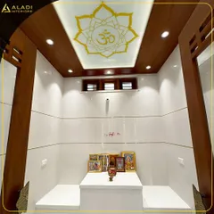A minimalist and modern puja space with a beautiful lotus and 'Om' motif on the backlit ceiling. The clean white tiles and simple wooden frame create a serene and peaceful environment.