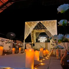 This rooftop proposal setup is designed for a magical evening. A fairy-light canopy leads to a "Will You Marry Me?" neon sign, with an aisle of large LED pillar candles creating a warm and inviting path.