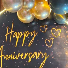 A close-up of the 'Happy Anniversary' neon sign against a sparkling black backdrop, adding a personalized and warm glow to the celebration.