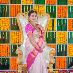 The mother-to-be looking regal on a throne-like chair, set against a festive backdrop of marigold flowers. This is a classic shot from a traditional baby shower ceremony.