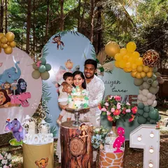 A happy family celebrating their little one's first birthday with our jungle theme decor. We used custom backdrops with cute safari animals, wood-textured pedestals, and a marquee number '1' to complete the look.
