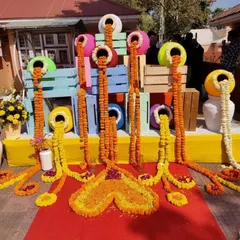 A creative and artistic floral installation for a Mehendi or Haldi event, with marigold garlands appearing to flow out of colorful pots.
