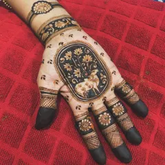 A unique design featuring a cow, a symbol of grace, as the central motif. The figure is surrounded by lotus flowers and set in an oval frame, creating a piece of art on the hand.