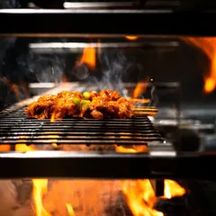 Capturing meat grilling over a live flame tells a powerful story of flavor. The smoke and fire in this shot for a Michelin-starred restaurant collaboration instantly communicate a deep, smoky taste.