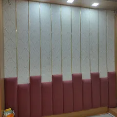 For this bedroom, I created a floor-to-ceiling upholstered wall. The design mixes a patterned wallpaper with vertical panels, slim gold metal inlays, and a soft pink padded base for a complete, luxurious headboard wall.