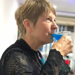 A guest savoring a vibrant blue cocktail during a party. My aim is to create drinks that are not only delicious but also a conversation starter.