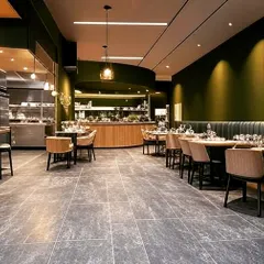 A modern restaurant design with an open kitchen concept. The olive green walls, dark flooring, and mix of booth and chair seating create a contemporary and dynamic dining space.