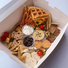My dog-friendly grazing board is a feast for the senses. This one is packed with homemade chicken jerky, dehydrated anchovies, bread sticks, gourmet dips, carob peanut butter cups, and even a monster waffle burger.