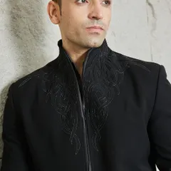 A close-up of the abstract, handcrafted embroidery on the collar. This detail adds a touch of artisanal texture to the otherwise minimalist and bold black jacket.