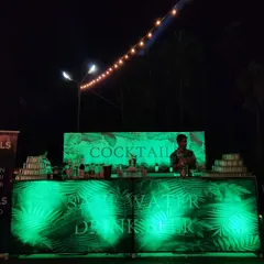 For the 75th birthday party, we set up a tropical-themed cocktail bar. The bar was backlit with green lighting and featured custom graphics, providing a dedicated and stylish space for drinks to be served.