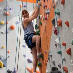 A smiling climber pauses on his way up the wall. The sense of accomplishment and fun is what keeps our community coming back for more.