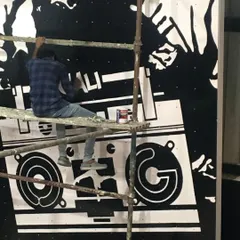 One of our artists on scaffolding, hand-painting the fine details of a large boombox mural for a gym. Even for large graphic pieces, we ensure every line is sharp and clean.