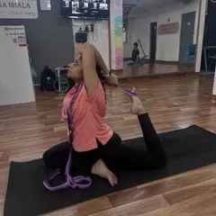 Using a yoga belt is an excellent way to work on flexibility. Here, a student uses a belt to gently deepen her stretch in Eka Pada Rajakapotasana (Pigeon Pose).