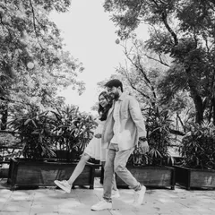 A playful, candid moment of a couple walking, captured in black and white. The monochrome effect adds a classic, storytelling feel to this joyful image.