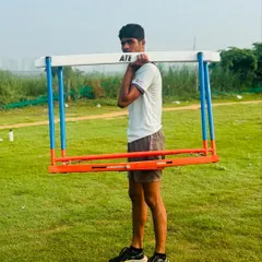 An athlete carries a hurdle as part of a strength and conditioning drill. This builds functional strength specific to the demands of a hurdler.