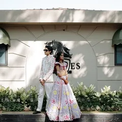 A stylish, full-length portrait of the couple at their carnival-themed event. Their confident poses and unique outfits showcase their modern and fashionable style.
