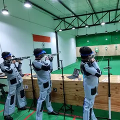 A team of rifle shooters practicing in unison, all wearing their official shooting jackets and trousers for optimal stability and form.