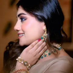 A detailed side profile, focusing on the exquisite craftsmanship of the emerald necklace and matching bracelet, capturing the luxury of the collection.
