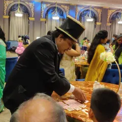 Performing card magic at a guest's table during a wedding reception. This kind of roaming magic is a great way to entertain guests during dinner or cocktails without interrupting the main event.